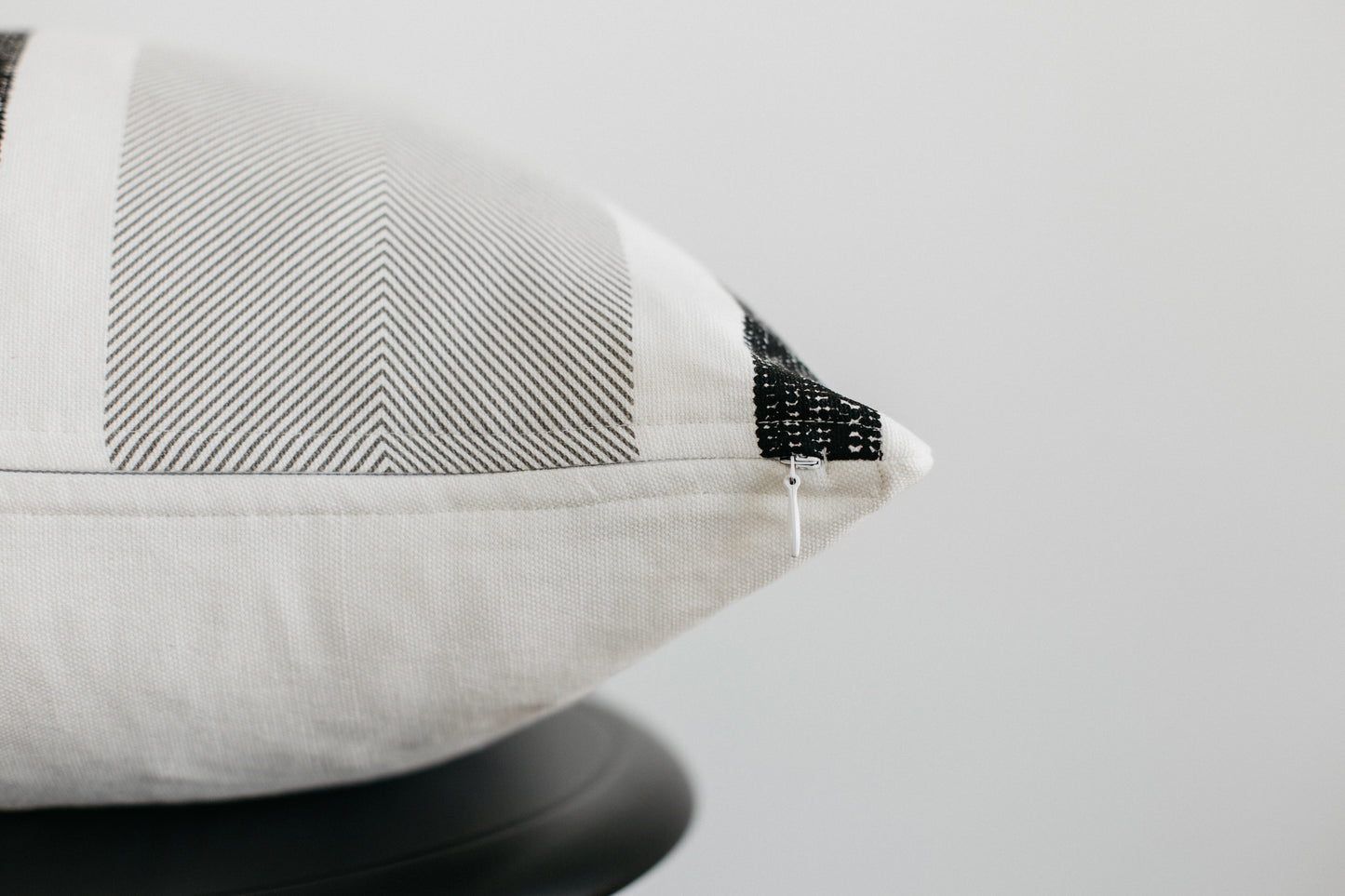 Cream and gray striped pillow with black mesh detail on corner seam.