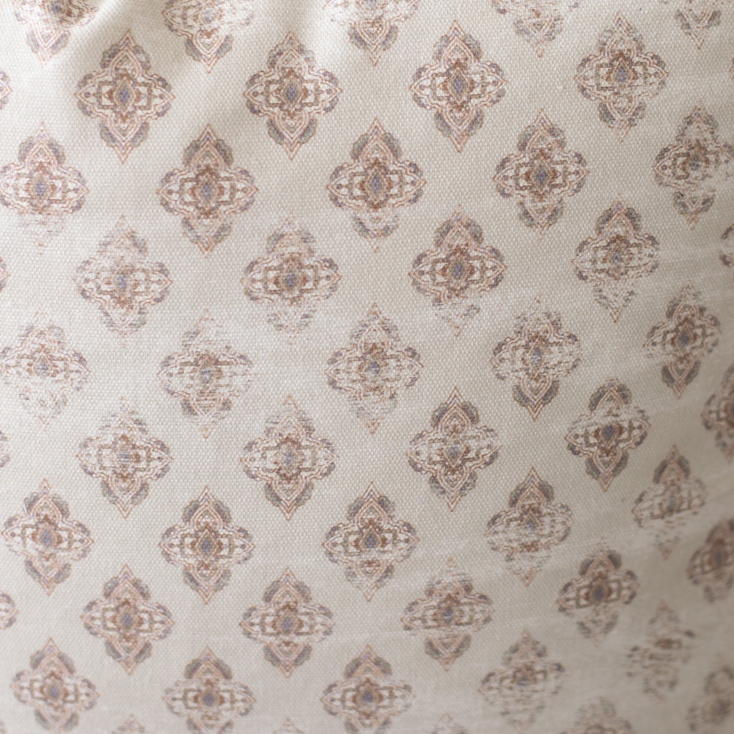 Four cream pillows with repeating taupe geometric diamond medallion pattern.