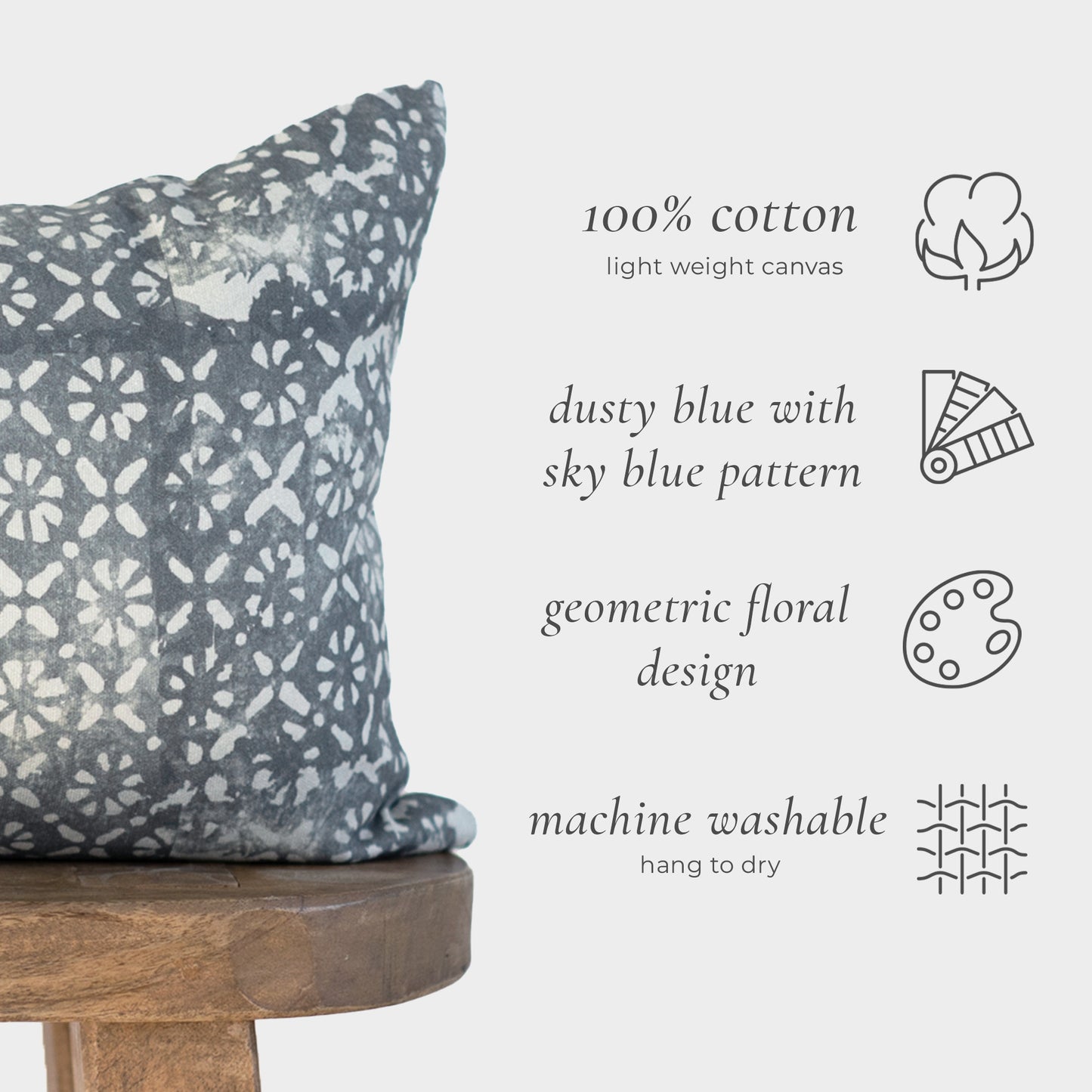 Rectangular lumbar pillow in dusty blue cotton with geometric floral pattern in sky blue, displayed on wooden stool.