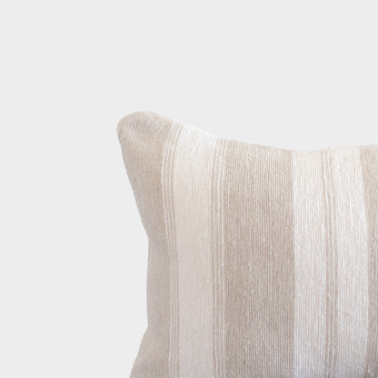Tan textured pillow with ribbed fabric surface and rounded corner detail against neutral background.