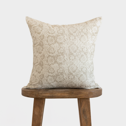 Cream pillow cover with beige damask floral pattern, displayed on wooden stool.