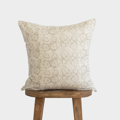 Cream pillow cover with beige floral damask pattern, displayed on wooden stool.