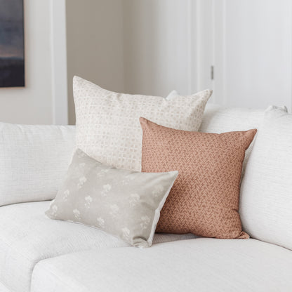 Gray lumbar pillow with floral pattern displayed on white sofa with coordinating pillows.
