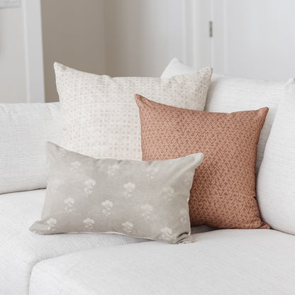 Gray lumbar pillow with white floral pattern displayed among neutral and terracotta pillows on a white sofa.