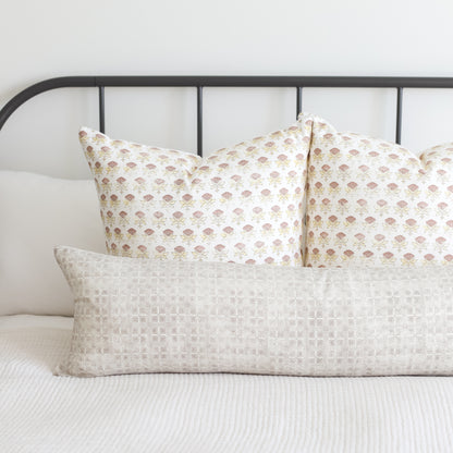 Rectangular lumbar pillow with light beige grid pattern displayed on bed with coordinating floral pillows.