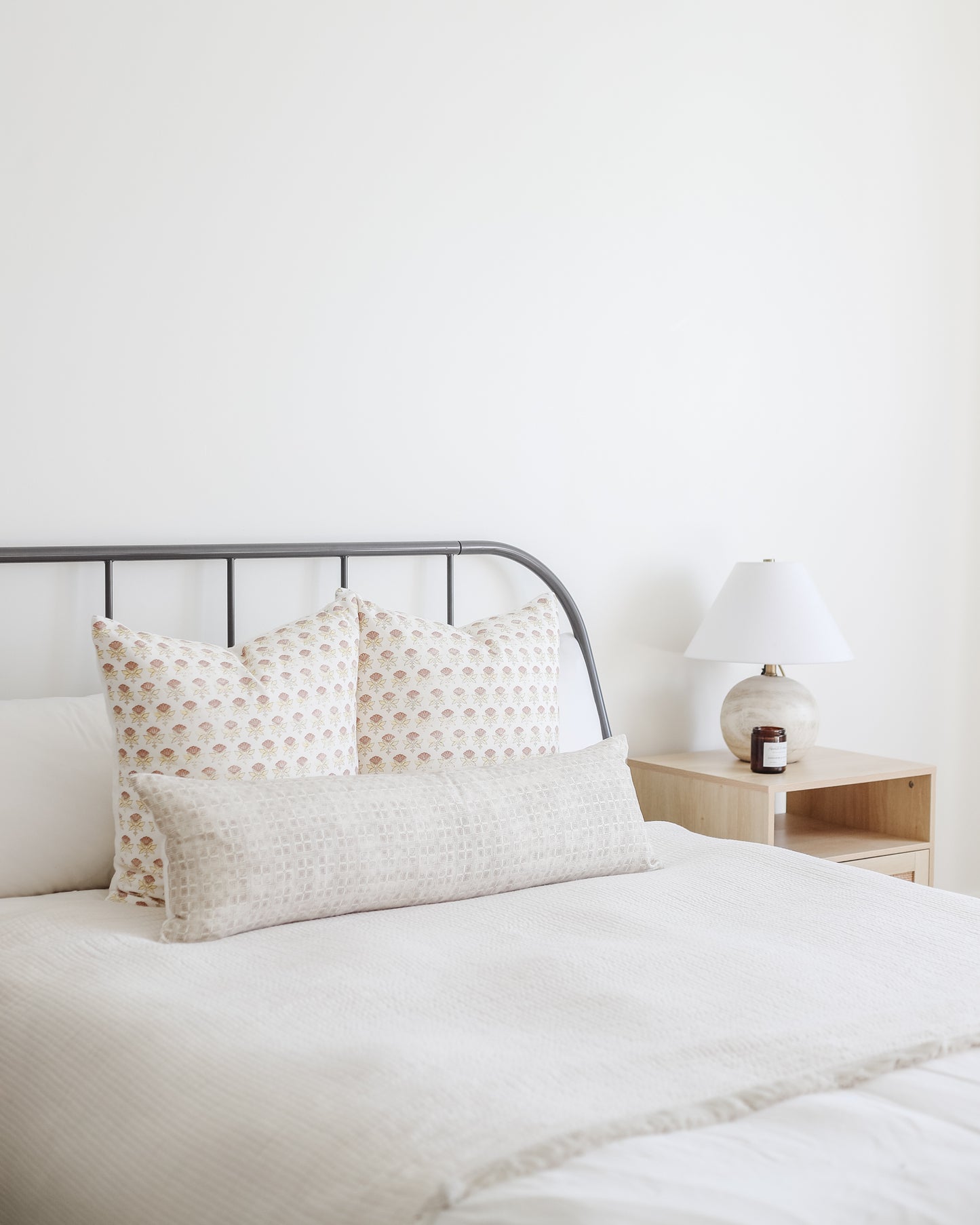 Rectangular lumbar pillow with beige grid pattern displayed on bed with matching square pillows.
