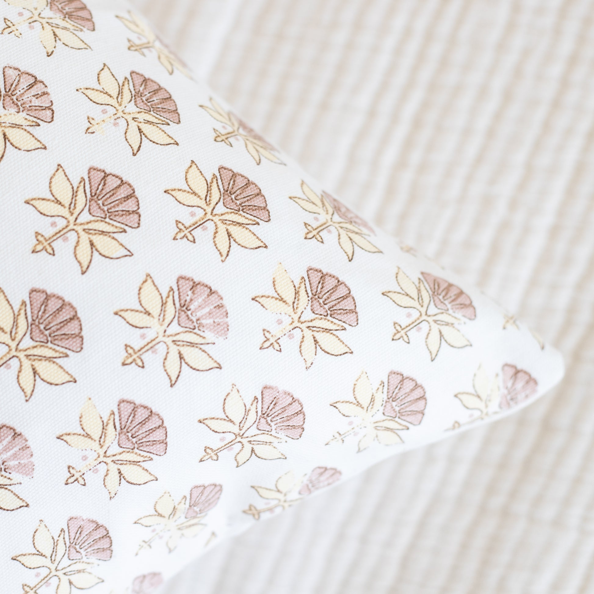 White fabric with tan and mauve floral pattern featuring fan-shaped flowers and leaves.