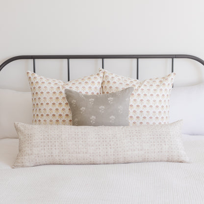 Rectangular lumbar pillow with neutral grid texture displayed on bed with patterned pillows.
