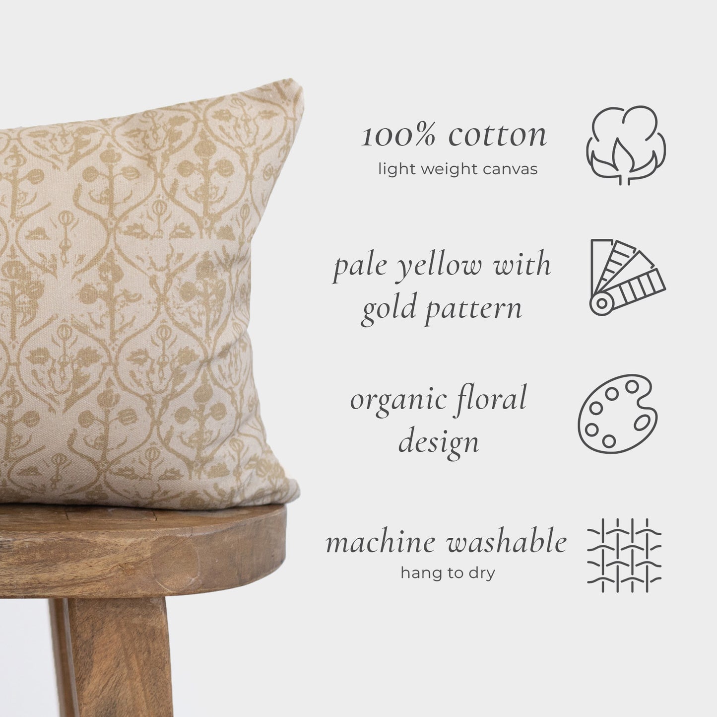 Pale yellow cotton pillow with gold floral damask pattern on wooden stool.