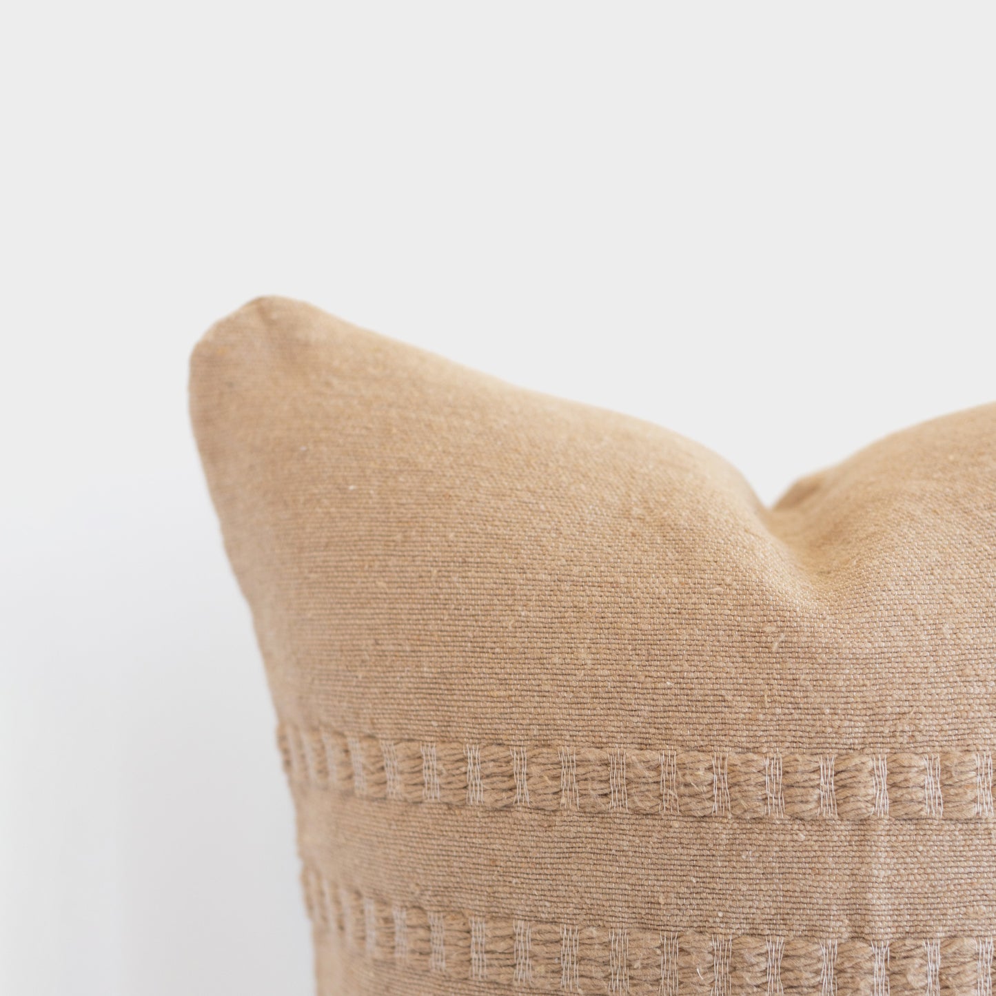 Tan woven pillow with textured geometric pattern bands across the center.