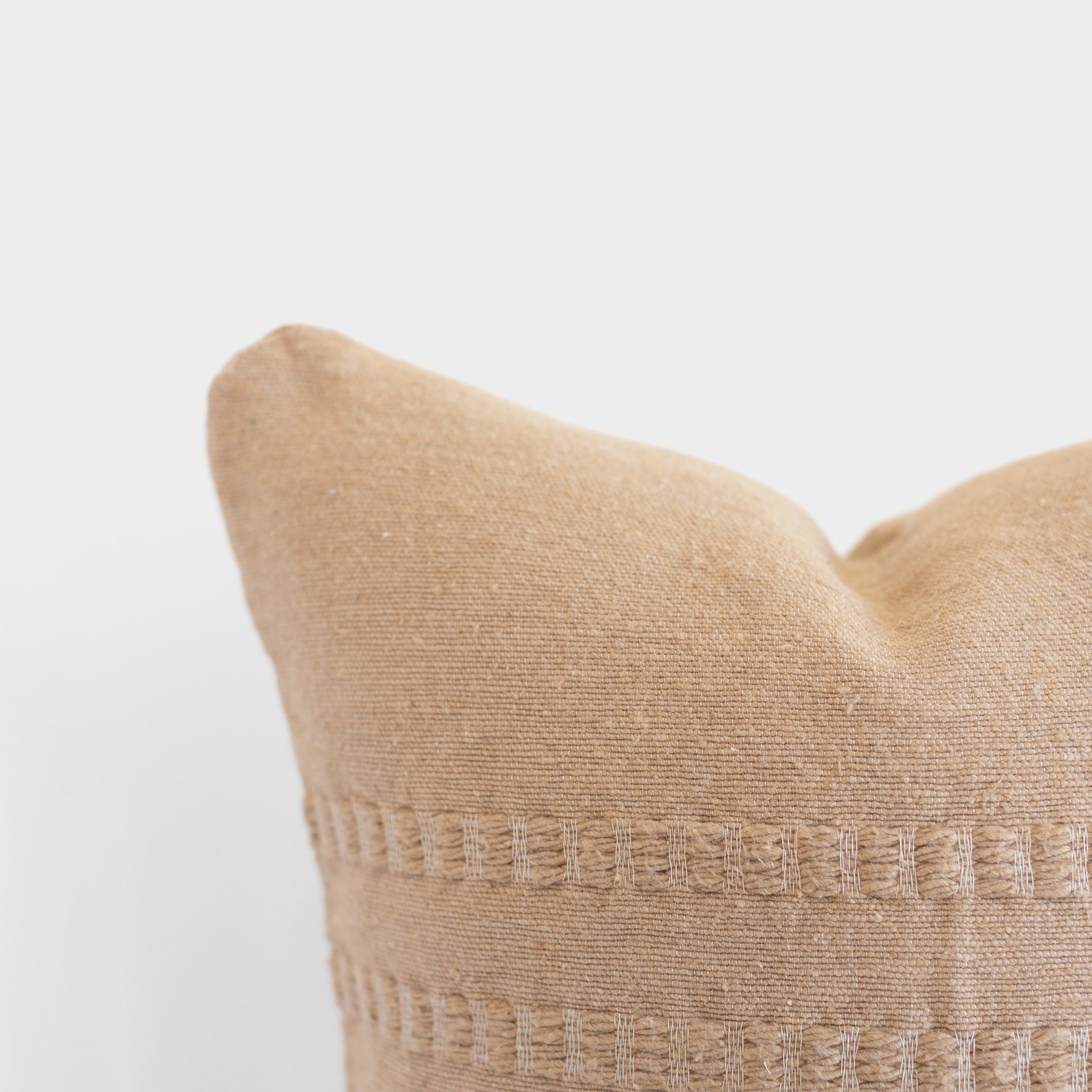 Tan woven pillow with textured geometric pattern bands across the center.