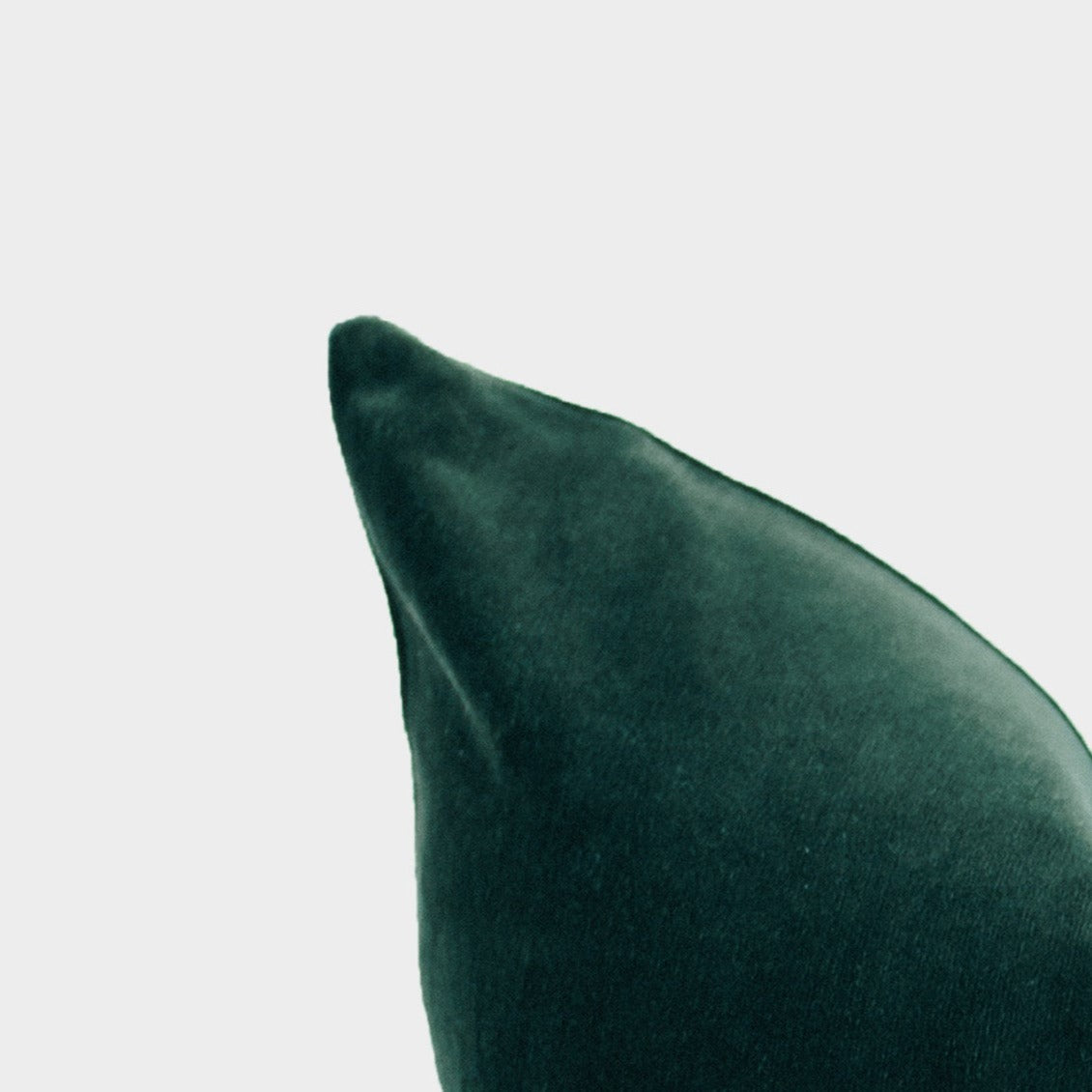 Green velvet pillow cover with pointed corner detail against white background.