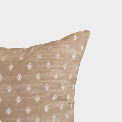 Beige throw pillow with white diamond pattern, shown at corner angle against neutral background.