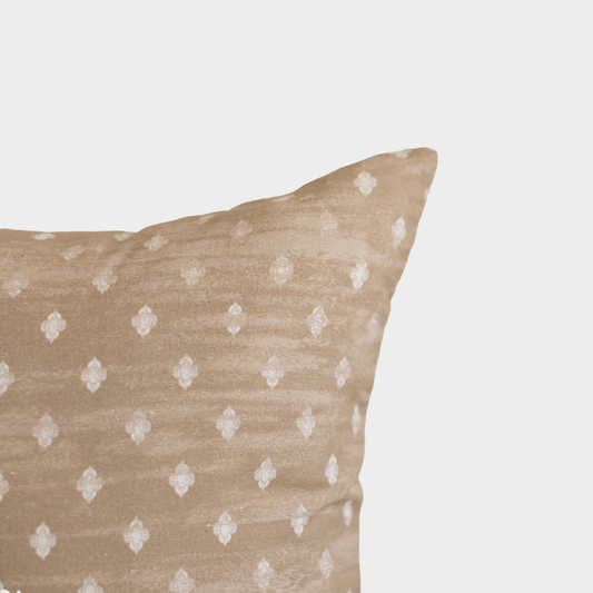 Beige throw pillow with white diamond pattern, shown at corner angle against neutral background.