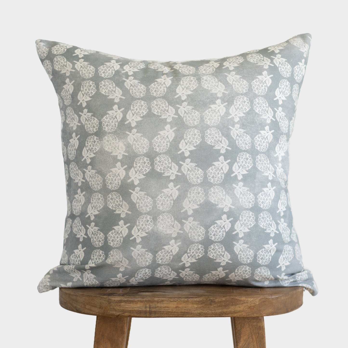 Gray cushion cover with cream turtle and leaf pattern, displayed on wooden stool.