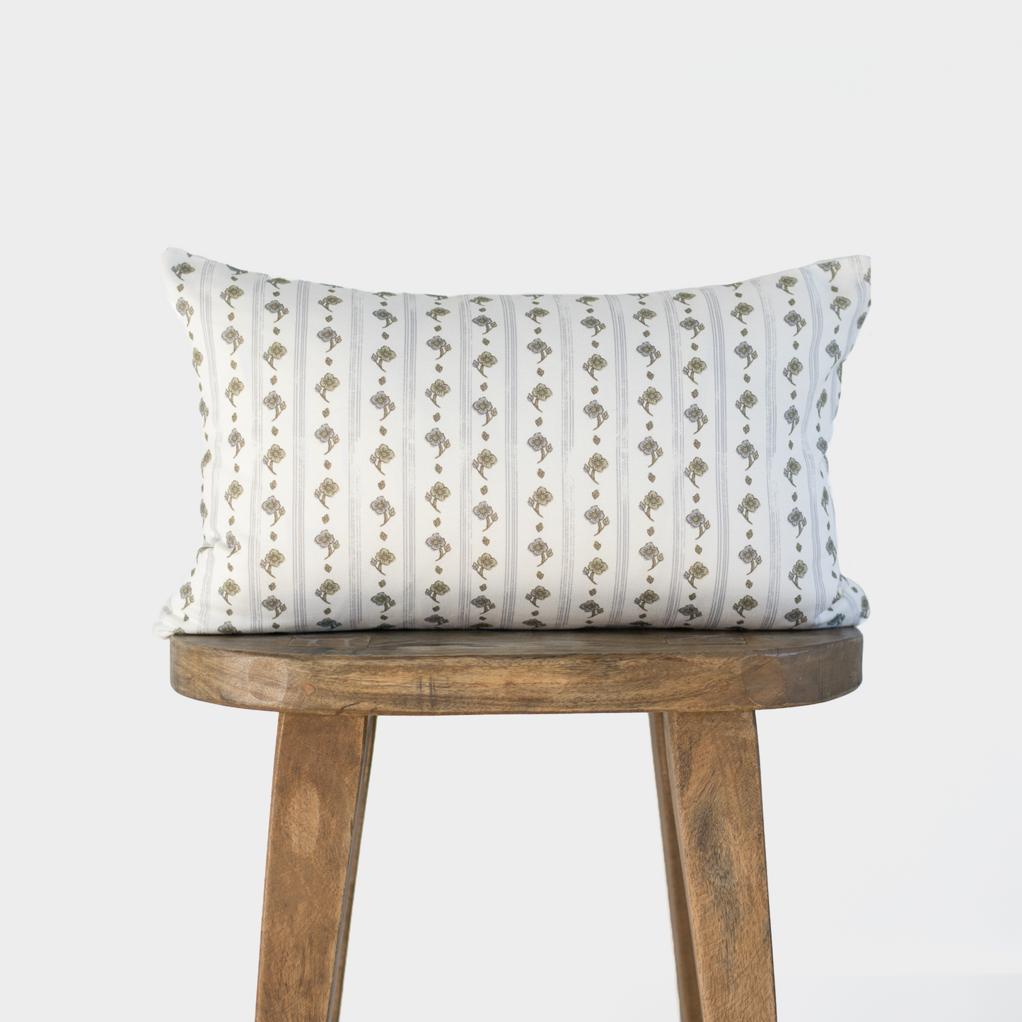 Rectangular lumbar pillow with vertical stripes alternating between white and taupe with small floral motifs, displayed on wo