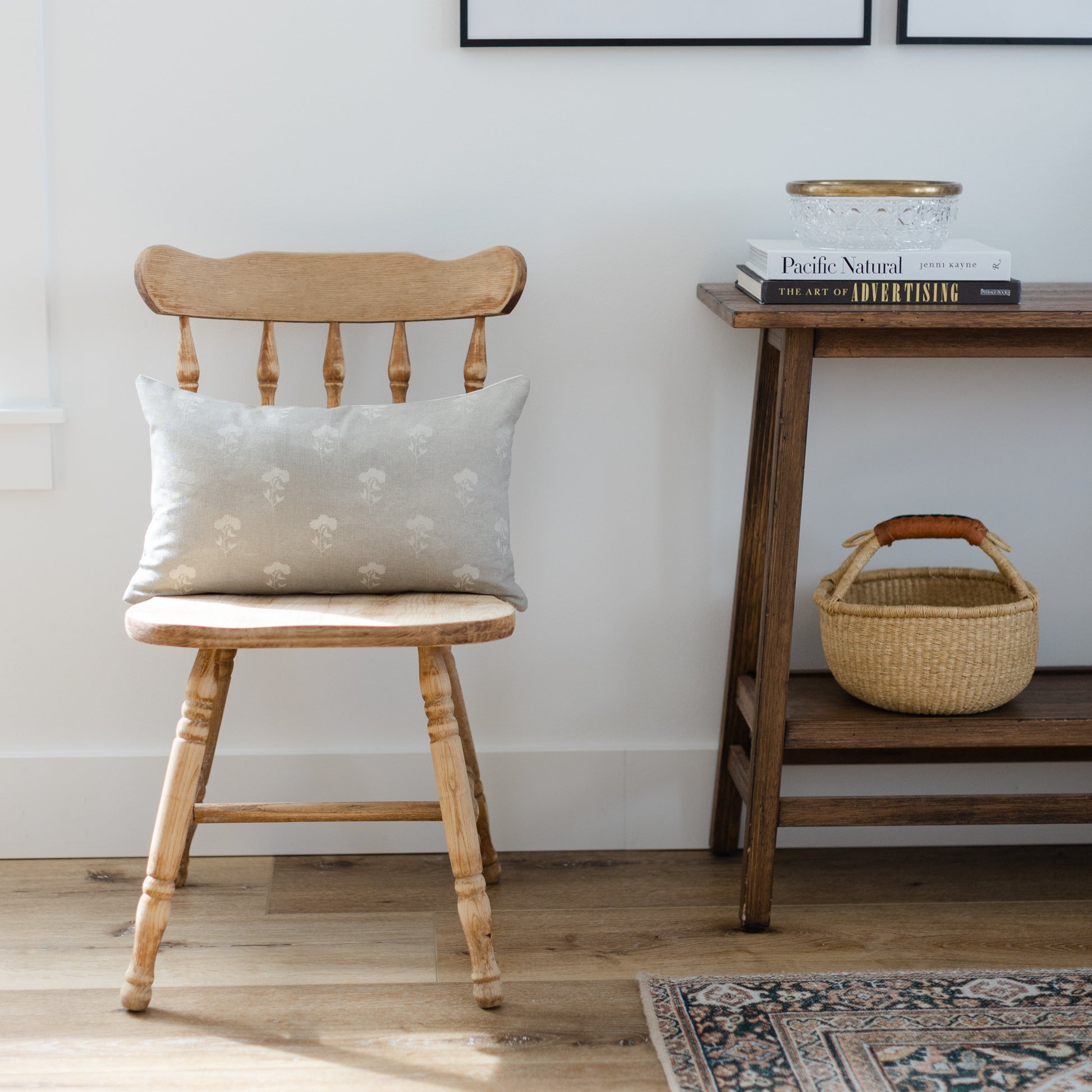Gray lumbar pillow with floral pattern displayed on wooden chair.
