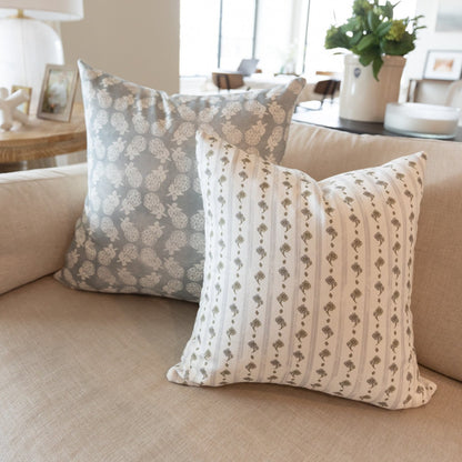 Cream and tan striped pillow with repeating floral motifs displayed on a beige sofa.