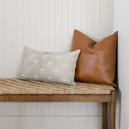 Gray lumbar pillow with white floral pattern displayed on wooden bench.