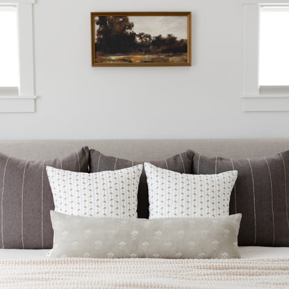 Gray lumbar pillow with small-scale floral pattern displayed on bed with matching decorative pillows.