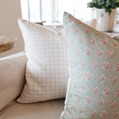 Four decorative pillows in neutral tones with grid and floral damask patterns, displayed on a beige sofa.