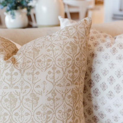 Four decorative pillows with damask and geometric patterns in beige and cream tones.
