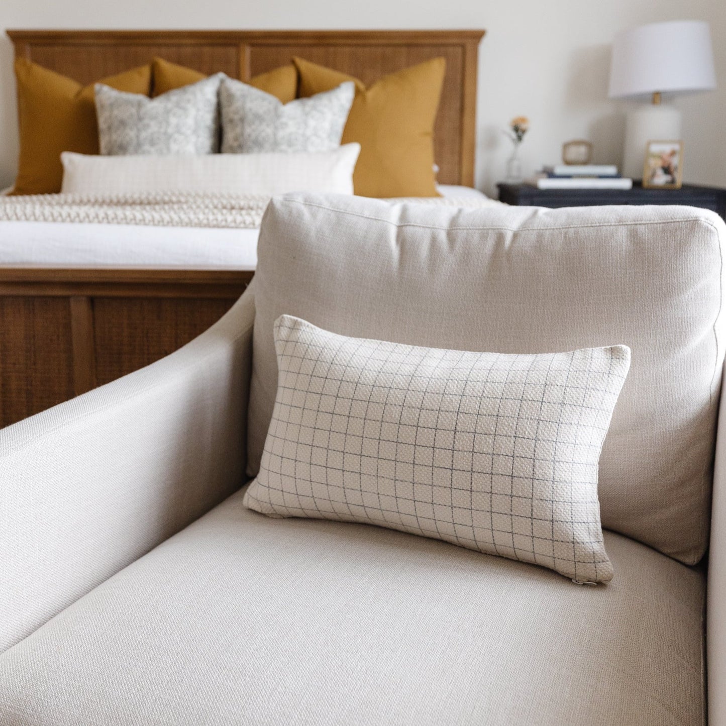 Cream lumbar pillow with subtle grid quilting pattern displayed on upholstered chair.