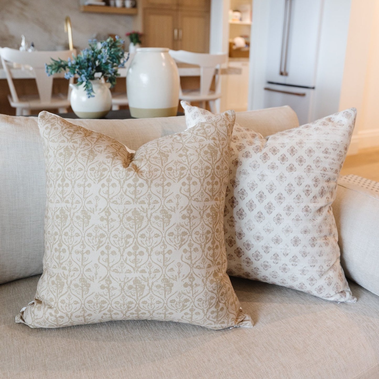 Four decorative throw pillows with tan and beige geometric patterns in 18" and 22" sizes arranged on a sofa.