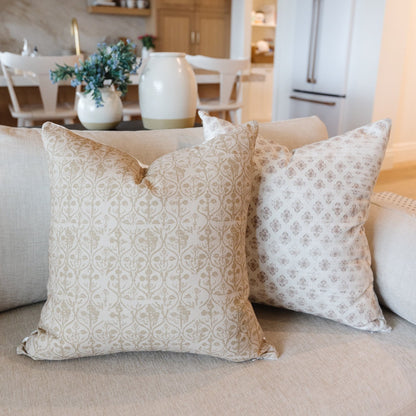 Four decorative throw pillows with tan and beige geometric patterns in 18" and 22" sizes arranged on a sofa.