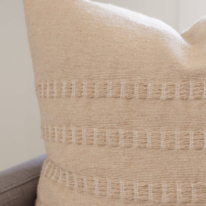 Tan woven pillow with three horizontal bands of geometric openwork detailing, 22 inches.