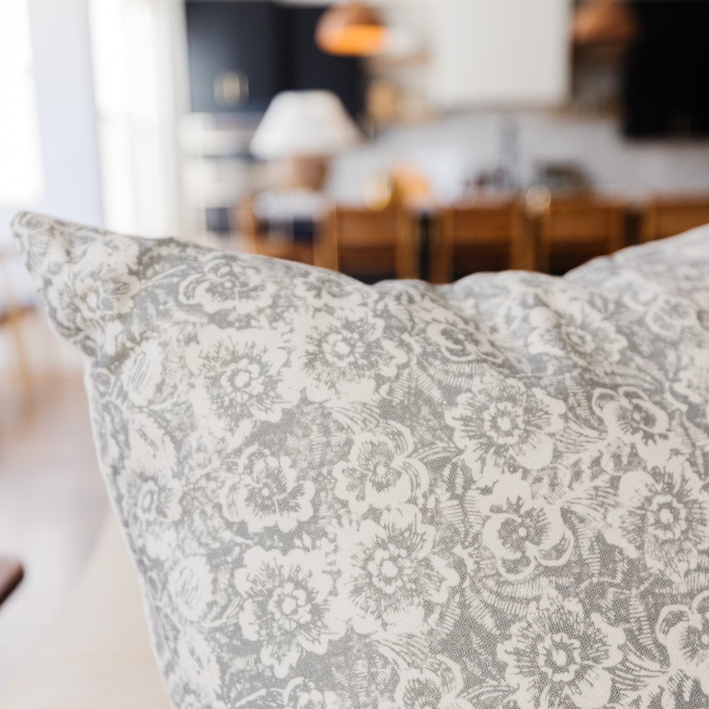 Gray and white floral patterned pillow with damask-style botanical design.