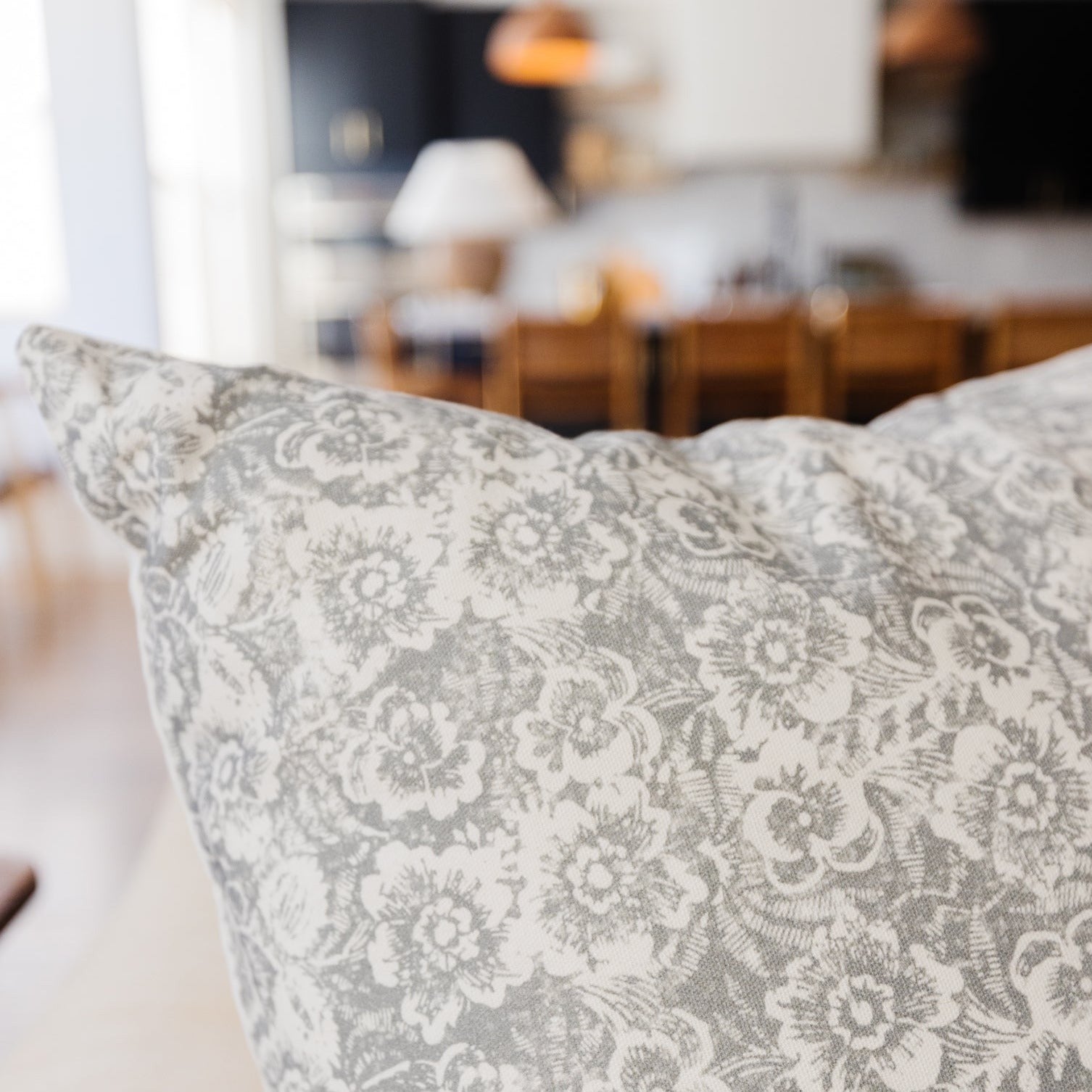 Gray and white floral patterned pillow with damask-style botanical design.