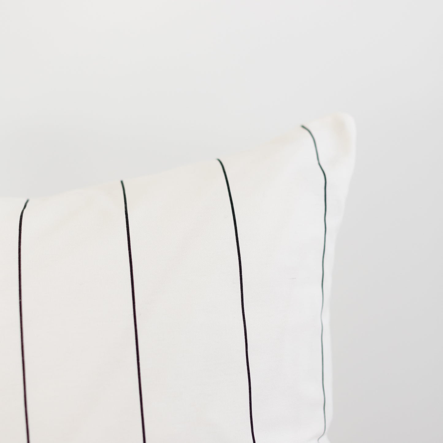 Cream-colored fabric with evenly spaced vertical pin stripes in black and gray tones.