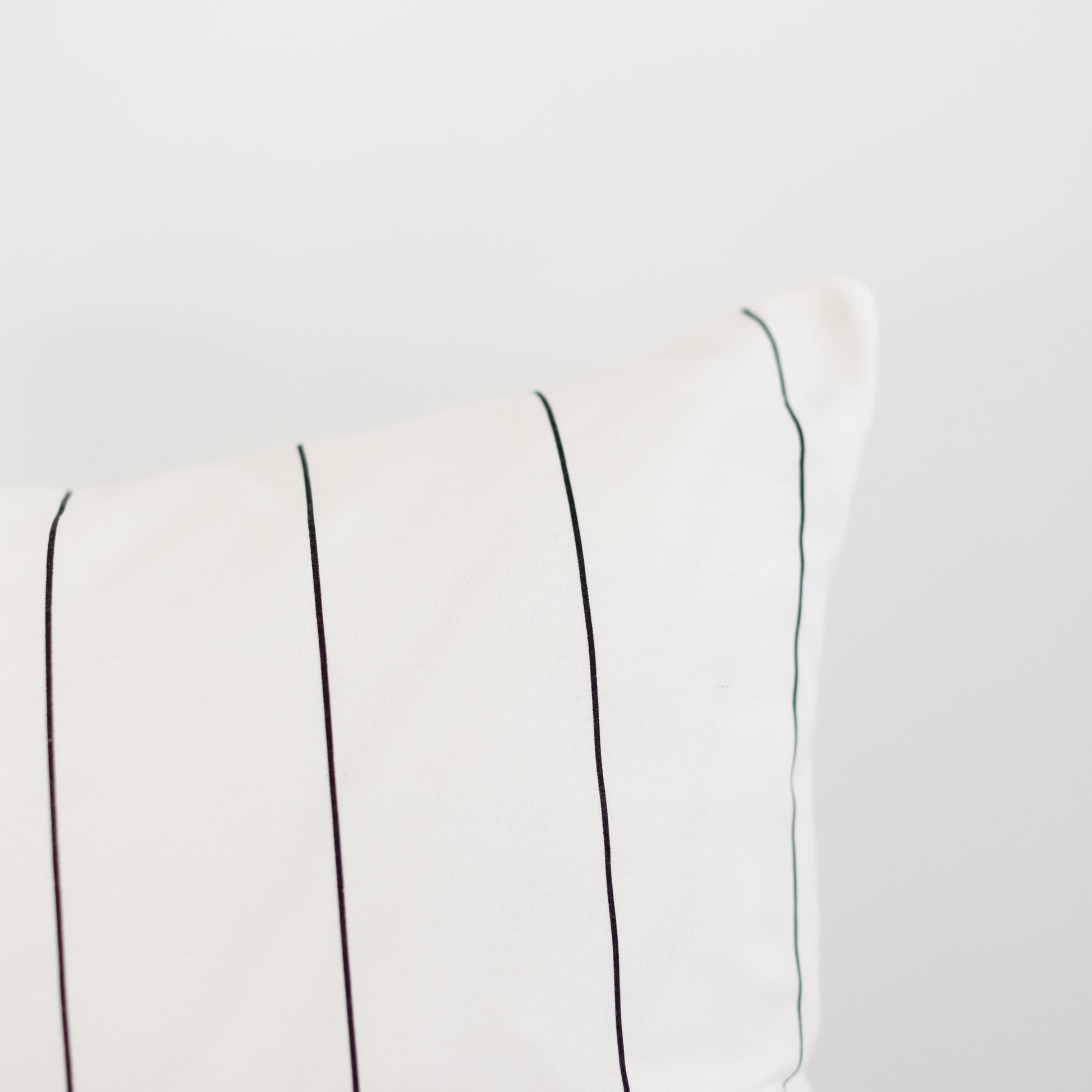 Cream-colored fabric with evenly spaced vertical pin stripes in black and gray tones.