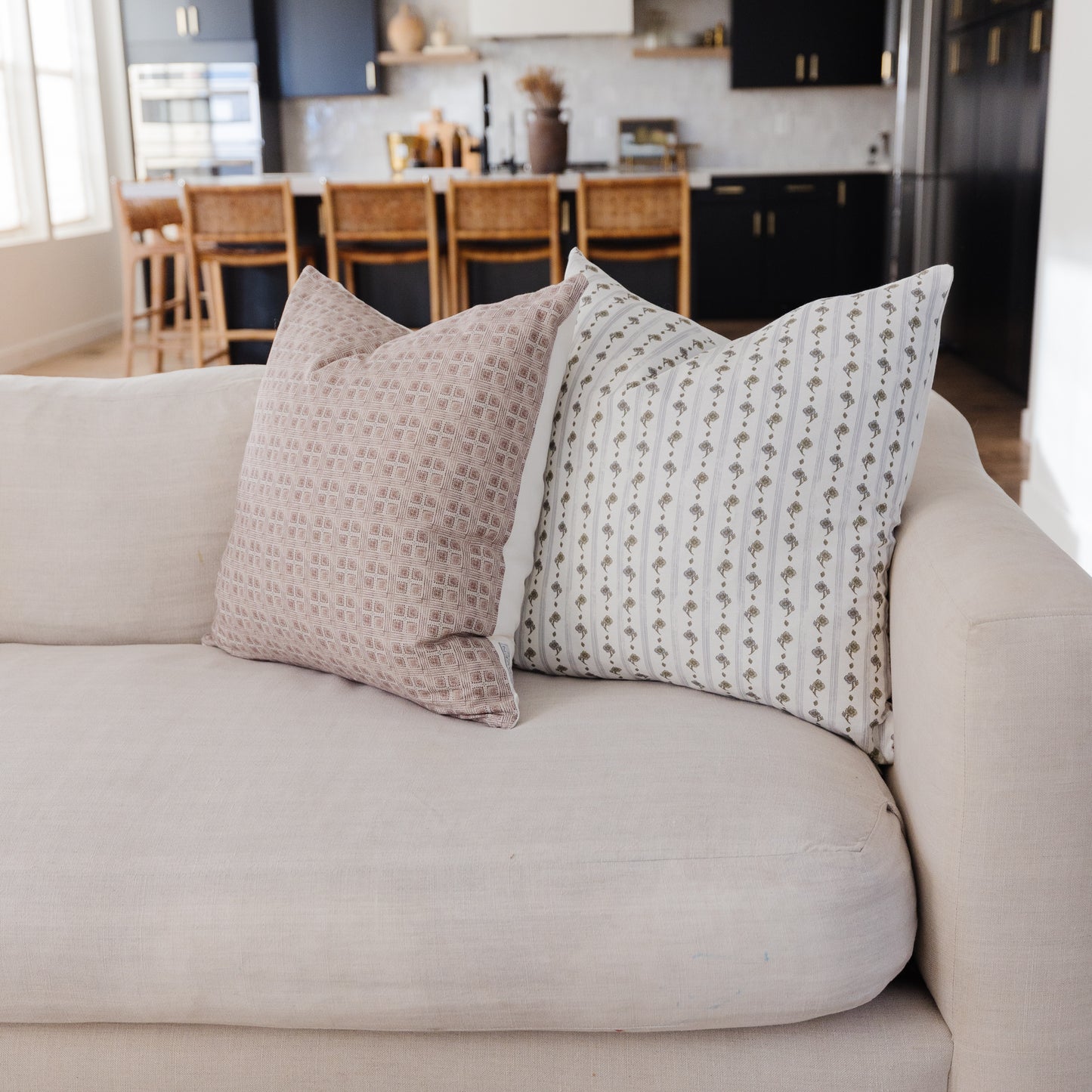 Two 18-inch decorative pillows with floral stripe patterns in neutral tones on a beige sofa.
