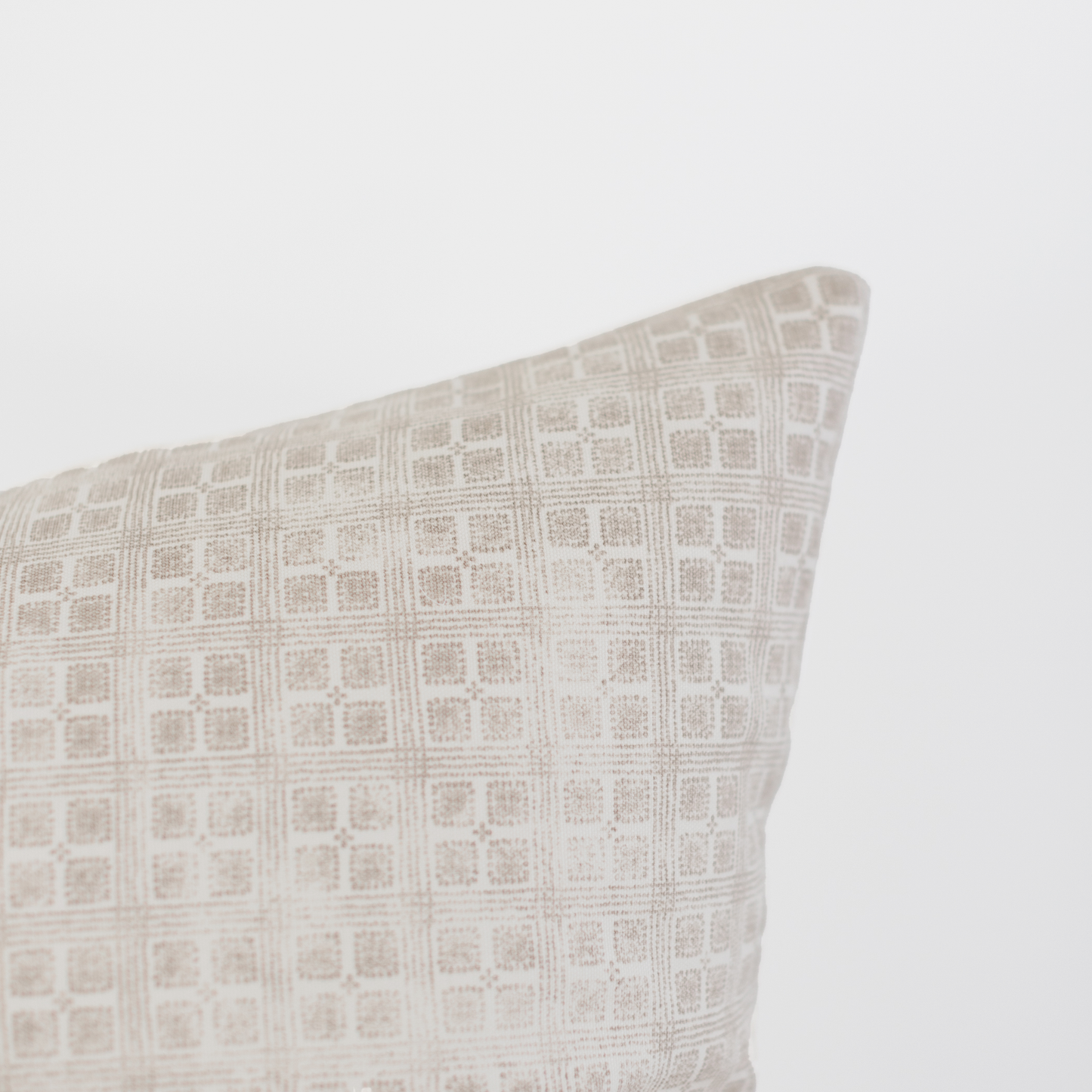 Beige and cream grid-patterned pillow with geometric square design and textured weave.