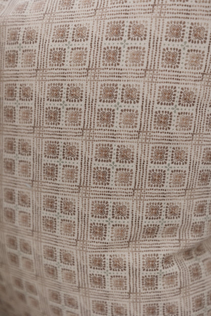 Brown and cream woven fabric with a repeating floral grid pattern in dotted texture.