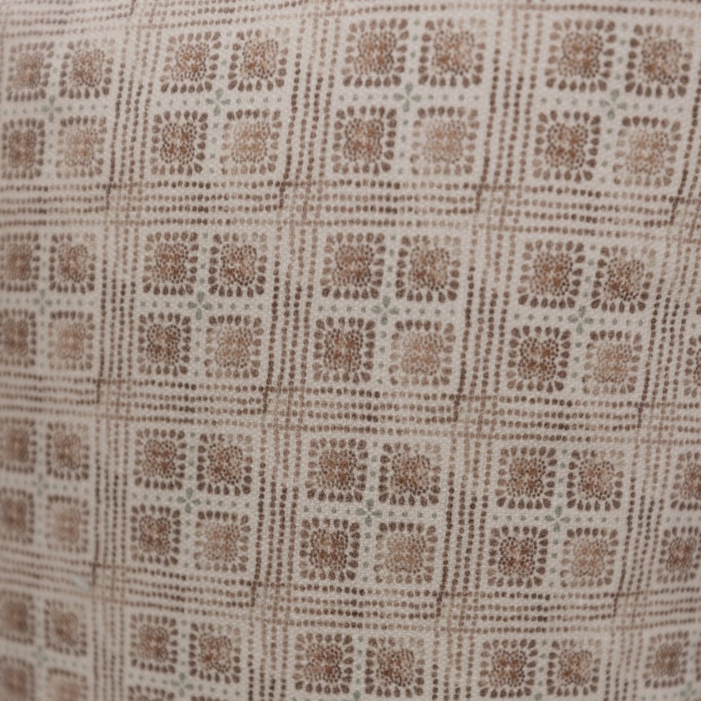Brown and cream lumbar pillow with geometric grid pattern of textured floral squares.