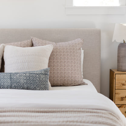 Brown woven grid patterned pillow displayed on a bed with white and blue patterned pillows.