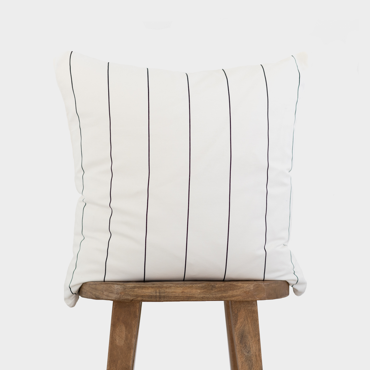 Cream cushion with black vertical pinstripes on wooden chair back.