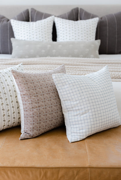 Four decorative pillows in varying patterns including geometric grid, textured weave, and small-scale prints in neutral tones