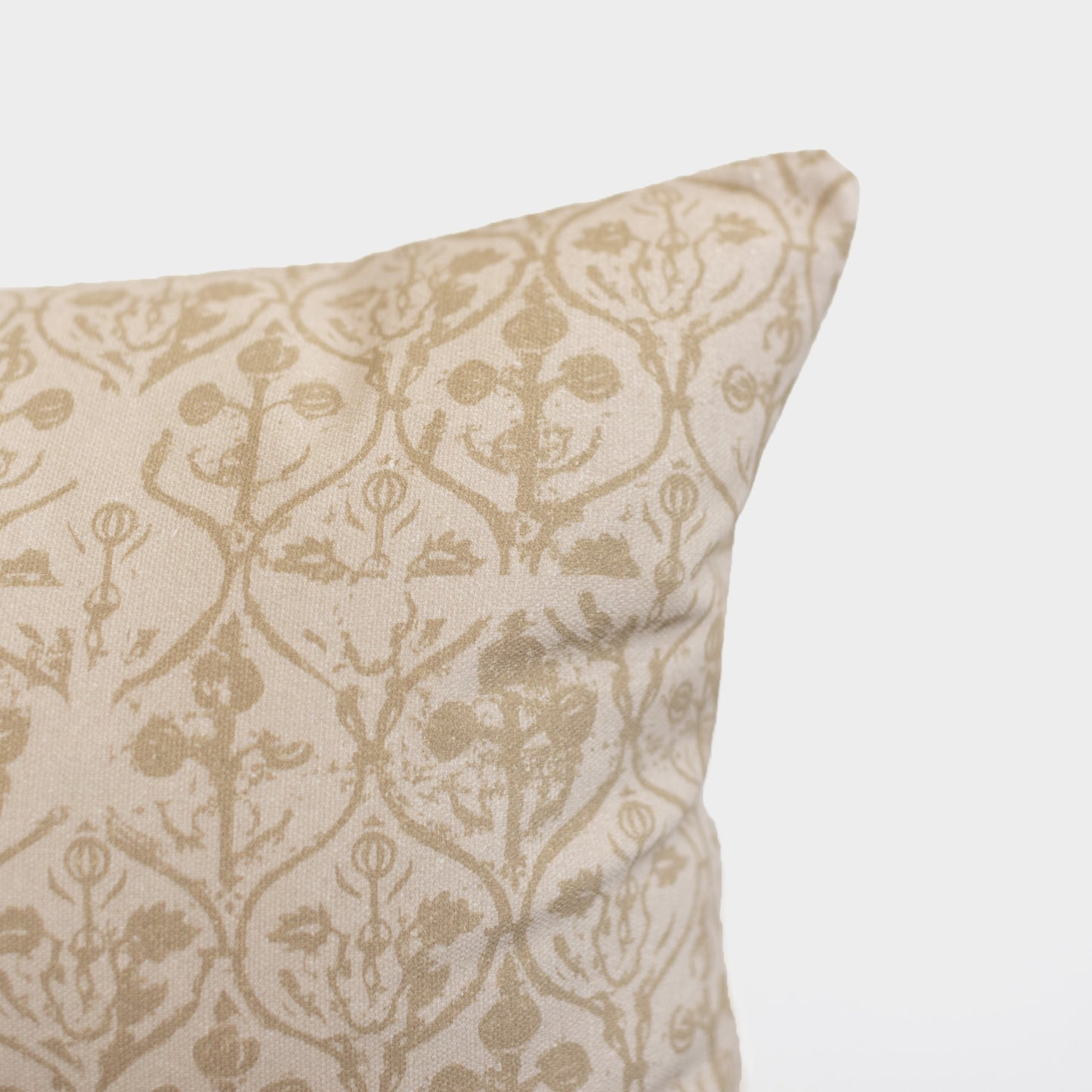 Cream and tan floral patterned pillow with symmetrical botanical design and decorative ornamental details.