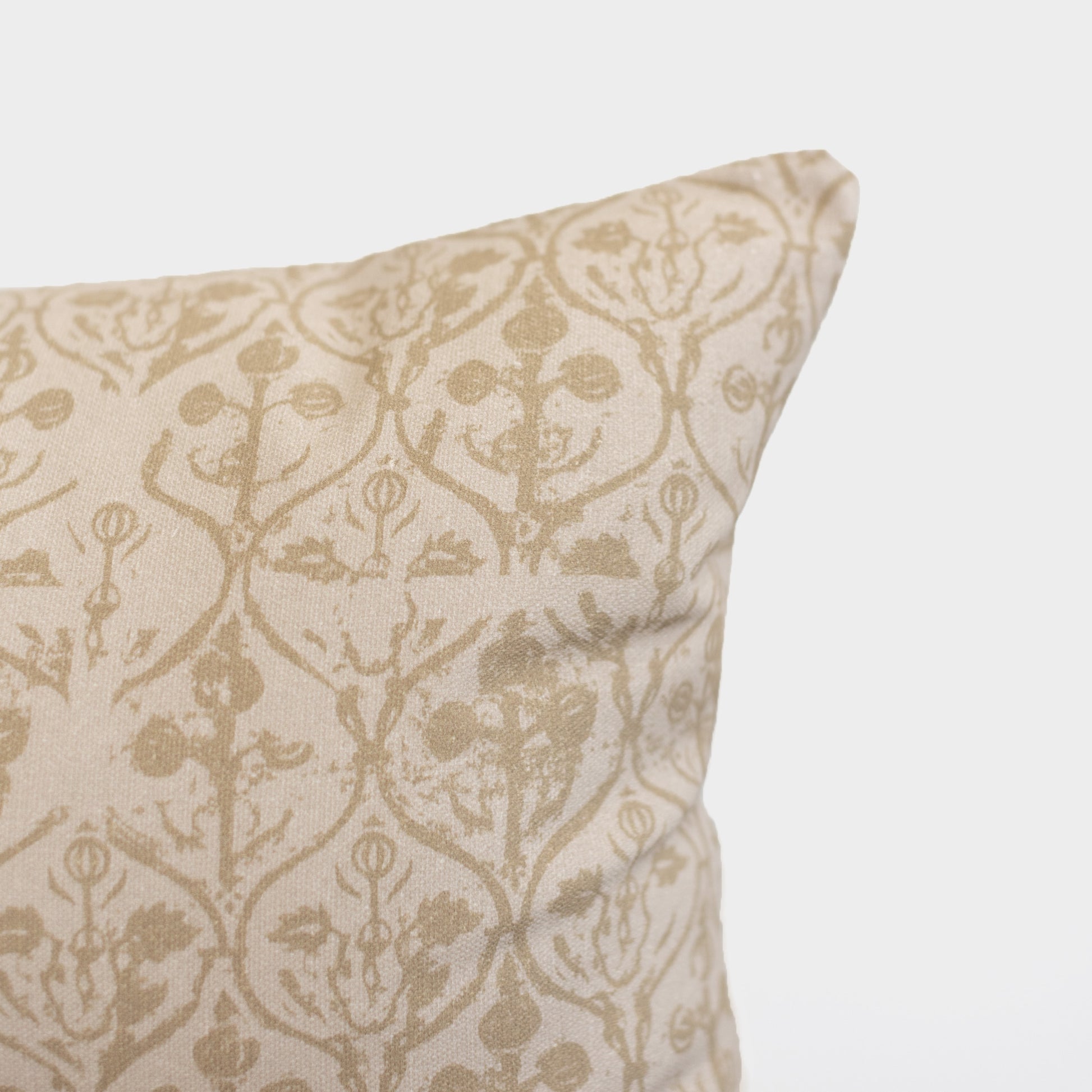 Cream and tan floral patterned pillow with symmetrical botanical design and decorative ornamental details.