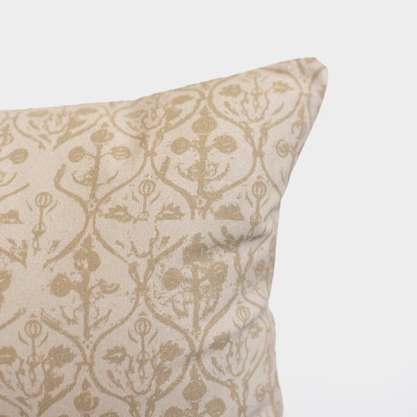 Cream and tan floral patterned pillow with symmetrical botanical design and decorative ornamental details.