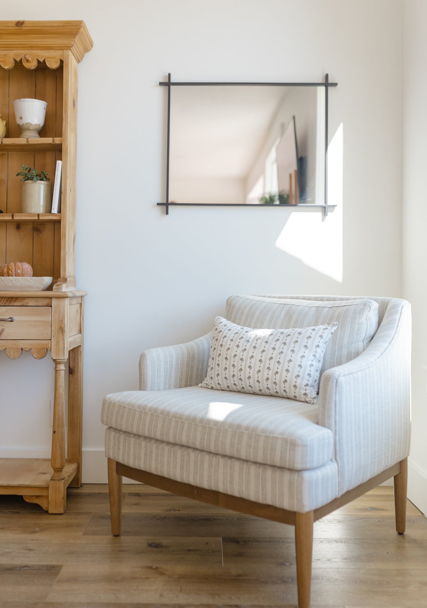 Rectangular lumbar pillow with cream and blue floral stripe pattern on striped armchair.