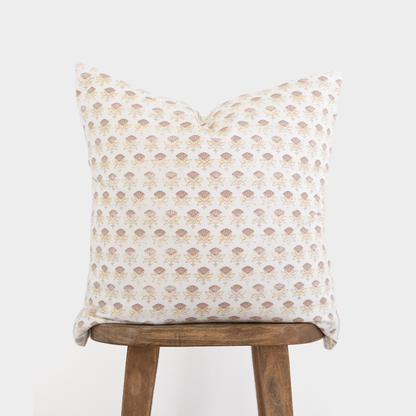 White pillow with an all-over tan floral fan pattern displayed on a wooden stool.