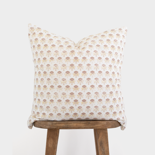 White pillow with an all-over tan floral fan pattern displayed on a wooden stool.