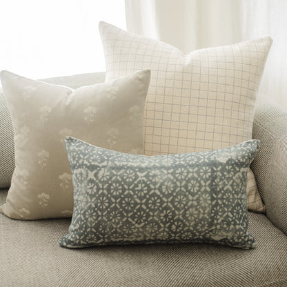Rectangular lumbar pillow with teal and cream geometric damask pattern on a gray upholstered surface.