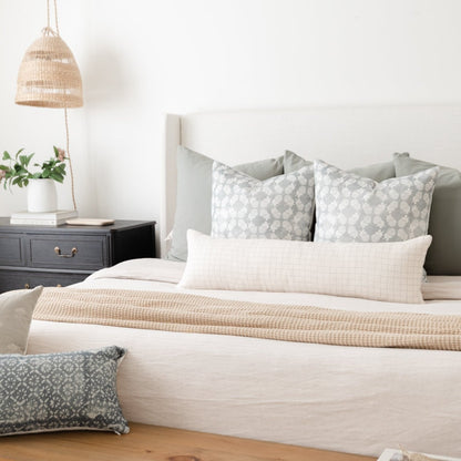 Lumbar pillow with geometric grid pattern in gray and white, displayed on bed with coordinating bedding.