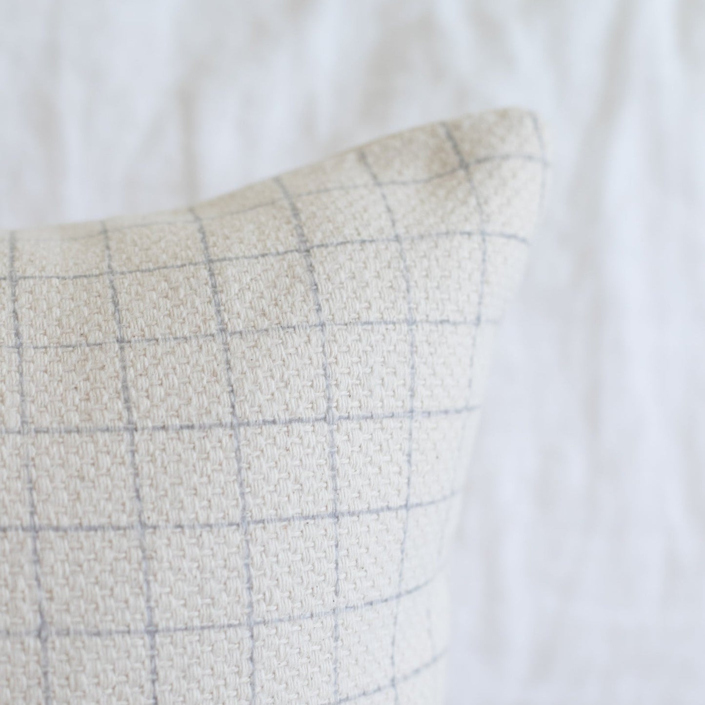 Beige lumbar pillow with gray grid pattern on linen fabric.